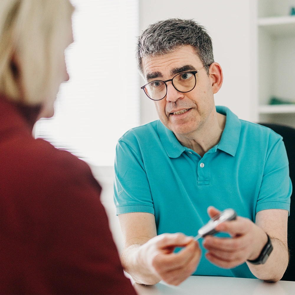 Arzt zeigt Zuckermessgerät einer Patientin